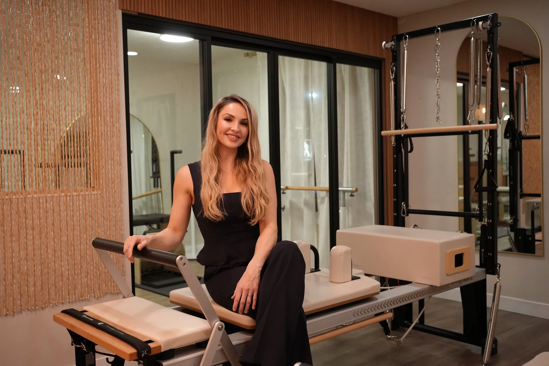 Dr. Maria Zazzi, founder of All Well Life, seated on a Reformer in the Pilates studio